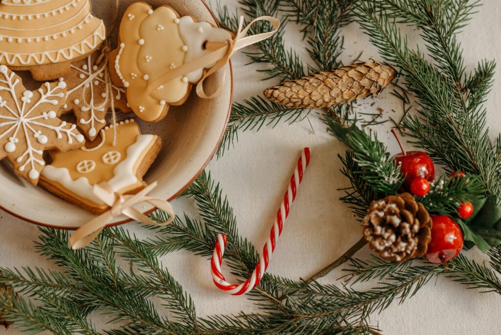 Cozy Christmas scene with cookies, pine branches, and candy cane on a table.